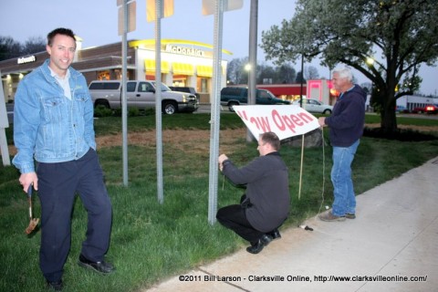 Larson Enterprises owner Eric Larson stands in front of his business as an open sign is hung out by the street