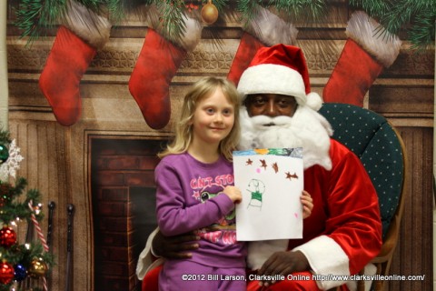 A young girl presents her Christmas drawing to Santa Claus A young girl presents her Christmas drawing to Santa Claus