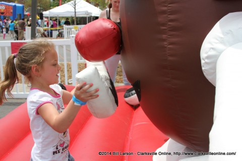 A young girl places lips on a giant Mr. Potato Head Inflatable.