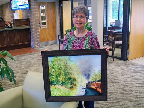 Kay Limirande holding one of her paintings in Planters Bank.