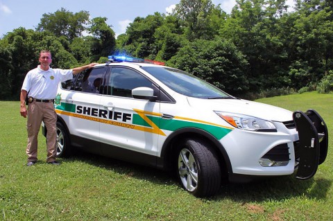Sheriff John Fuson unveils the new fleet vehicle, a 2014 Ford Escape that costs less, has a higher mile per gallon rating and is more environmentally friendly.