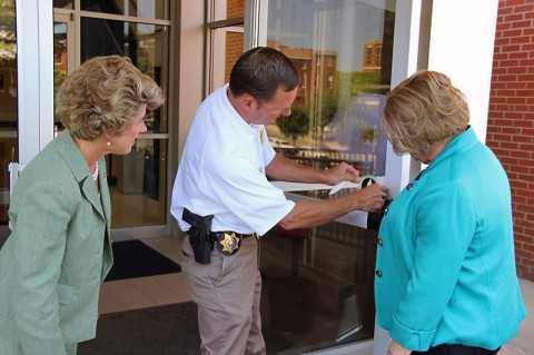 Bowers and McMillan assist Fuson in applying the sticker signifying green certification on the Public Safety Complex.