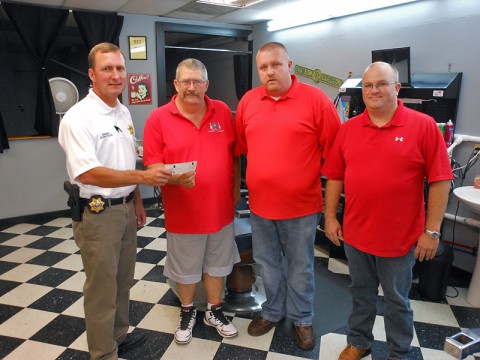 Sheriff John Fuson is presented with a check from Uncle Joe’s Barber Shop in honor of Deputy David “Bubba” Johnson. Pictured are Fuson, Greg Cooper, Brad Young and Jonathon Uzzle.