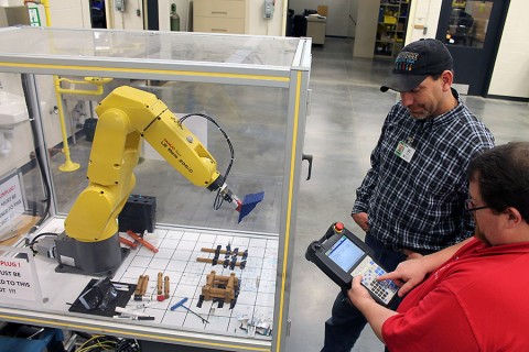 Industrial Maintenance/Electricity instructor Steve Shaw instructs student Greg Haler on the mechanical operations of robotics.