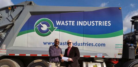 LEAP's Richard Garrett accepts a $5,000 check from Waste Industries General Manager Thane Harrison.