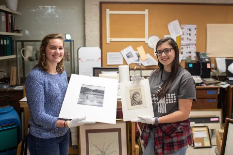 Austin Peay State University Art Students Sarah Potter and Katherine Tolleson hold their discoveries. Potter is holding a Philippe Halsman photo print of Winston Churchill, and Tolleson is holding a drypoint by Alphonse Legros.