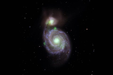 Bright green sources of high-energy X-ray light captured by NASA's NuSTAR mission are overlaid on an optical-light image of the Whirlpool galaxy (in the center of the image) and its companion galaxy, M51b (the bright greenish-white spot above the Whirlpool), taken by the Sloan Digital Sky Survey. (NASA/JPL-Caltech, IPAC)