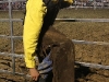 A cowboy puts his boot back on after it got pulled off by the muck in the ring