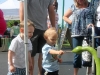 Two young boys inspect a snake made out of a gourd as dad and the crowd looks on