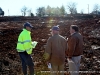 Construction company representatives talking as equipment works behind them in the construction zone