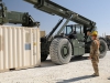 U.S. Army Spc. Casey E. Sleeman, a native of Sioux Falls, SD, and a cargo specialist, ground-guides and conducts arm and hand signals for U.S. Army Spc. Kevin E. Berry, a native of Grantsburg, WI, and a materials handler equipment operator, as Berry prepares to pick up a container with a Kalmar RT-240 Rough Terrain Container Handler. (U.S. Army photo by Sgt. Sinthia Rosario, Task Force Lifeliner Public Affairs)