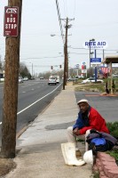 A man waits for the bus while looking for a job