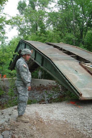 Sgt. Terry Bell, 190th Engineer Company, 230th Engineer Battalion, 194th Engineer Brigade, guides a Armored Vehicle Launched Bridge into place across a creek at the Killebrew detour off Angels Road at Fort Campbell today.