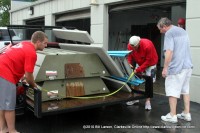 Bill Roberts (Right) looks on as two of his employees secure items on the back of a trailer for relocation