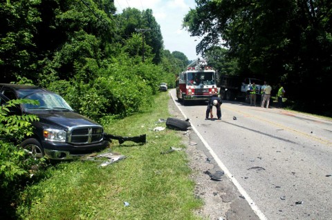 A CPD officer measures skid marks at the site of a collision of a pickup truck and a dump truck