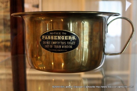 A brass chamber pot featuring a notice to passengers