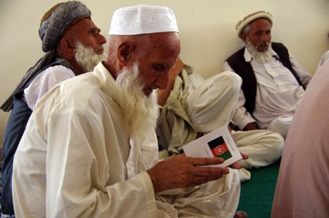 An elder reads a copy of the Afghan constitution as he joins more than 100 elders affected by the recent operations in eastern Kunar province who gathered in the Shura hall of the Marawara district center July 10th. The Kunar Provincial Reconstruction Team  tutored the elders about Afghan law and government. (Photo by Abraham Sutherland, Kunar Provincial Reconstruction Team)