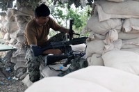 An Afghan National Army soldier inspects and cleans his weapon from the safety of his fighting position above the Marawarah District. Coalition forces pushed insurgents out of the district only days earlier and are setting up permanent outposts to prevent insurgents from returning to the area. (Photo by U.S. Army Spc. Albert L. Kelley, 300th Mobile Public Affairs Detachment)