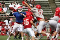 The red shirt QB lobs a pass in the face of a stiff defense.