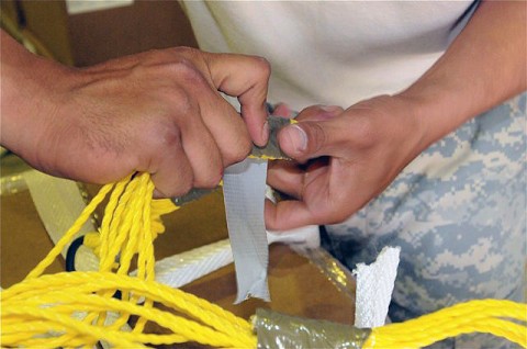 U.S. Army Staff Sgt. Carlos Gomez, wraps tape around parachute cords to keep them from getting tangled. The parachutes are attached to a pallet of supplies that will be dropped from an aircraft to ground troops at a remote forward operating base. (Photo by U.S. Army Sgt. Brent C. Powell, 3rd Brigade, 101st Airborne Division) U.S. Army Staff Sgt. Carlos Gomez, wraps tape around parachute cords to keep them from getting tangled. The parachutes are attached to a pallet of supplies that will be dropped from an aircraft to ground troops at a remote forward operating base. (Photo by U.S. Army Sgt. Brent C. Powell, 3rd Brigade, 101st Airborne Division)