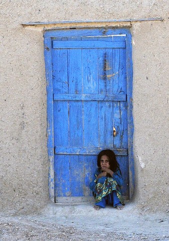 A village girl huddles near her home after an attack on Forward Operating Base Thunder, one of three bases insurgents attacked in eastern Afghanistan Sept. 24th. (Photo by U.S. Army Staff Sgt. Troy P. Johnson, 304th Public Affairs Detachment)