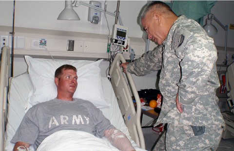 U.S. Army Maj. Gen. John Campbell, Commander of the 101st Airborne Division, stands over the bedside of U.S. Army Sgt. William Bickers Sept. 16th at Bagram Air Field in Afghanistan. Campbell presented Bickers with the Combat Infantryman’s Badge for his direct engagement with the enemy and a Purple Heart for being wounded in the line of duty while on a foot patrol in Andar District, Ghazni province. (U.S. Army photo by 1st Lt. R.J. Peek)