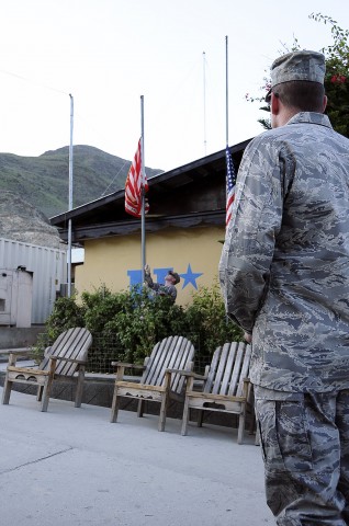 U.S. Air Force Chaplain (Capt.) James Anderson, the chaplain for Forward Operating Base Wright, looks on, U.S. Navy Lt. Cdr. Sean Gillespie lowers the PRT flag to half-mast as part of a ceremony commemorating Patriot Day and the ninth anniversary of the Sept. 11th attacks. (Photo by U.S. Air Force Capt. Peter Shinn, 734th Agri-Business Development Team)