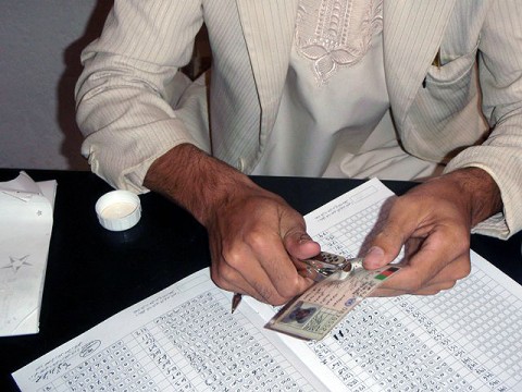 A polling center employee punches the registration card to verify the vote Sept. 18 for Deh Yak’s police chief, Haji Faiz Mohammad Tufan, who casted his vote at the Ramak Mosque polling center as a demonstration for others of how to complete the process. (Photo by U.S. Army 1st Lt. R.J. Peek, 3rd Battalion, 187th Infantry, 101st Airborne Division)