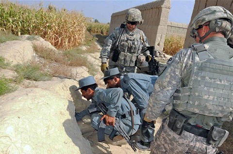 Soldiers from the 330th Military Police Company watch as two Afghan National Policemen investigate a large opening in the side of a wall while on a joint patrol Oct. 7th. The Soldiers are working closely with approximately 300 ANP to help train and advise them on all aspects of law enforcement operations. (Photo by U.S. Army Staff Sgt. Brent C. Powell, 3rd Brigade, 101st Airborne Division)