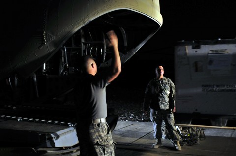 Spc. Robert Eayre, A Company, Task Force Troubleshooter Movement Control Team pax runner, assists the forklift driver and CH-47 Chinook helicopter crew chiefs load cargo in preparation for a night mission transporting both cargo and passengers from Kandahar Airfield, to an outlying forward arming and refueling point. 