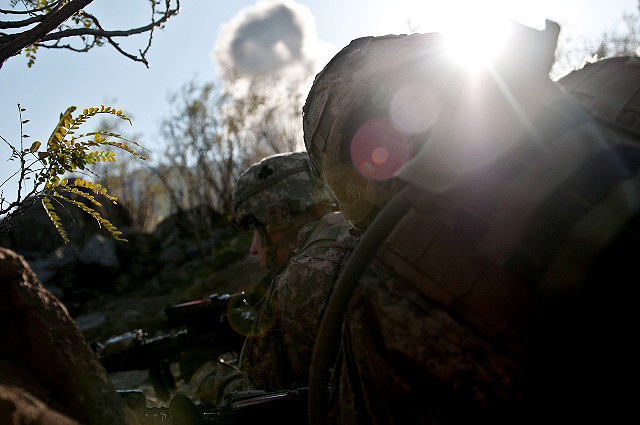 U.S. Army Staff Sgt. Clint J. Lyons (right), an infantry platoon sergeant from Gibsonville, NC, and U.S. Army 2nd Lt. Jacob Sass, a platoon leader from Chatfield, Minn., Task Force No Slack, get cover and fire back Nov. 7th as the sun crests the eastern ridge on a remote hilltop in the Shal Valley in eastern Afghanistan’s Nuristan Province and bombs explode in the distance. (Photo by U.S. Army Staff Sgt. Mark Burrell, 210th Mobile Public Affairs Detachment)