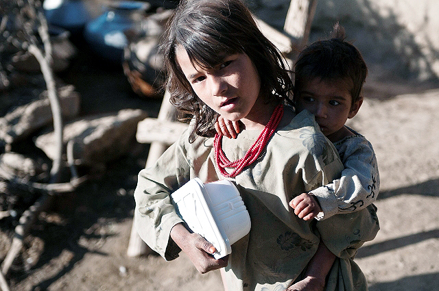 An Afghan girl clutches a box of food with one arm and her baby brother with another at a small village outcropping on a mountainside overlooking the Pech River Valley in eastern Afghanistan’s Kunar Province Nov. 23rd. Soldiers from Task Force Bulldog and Afghan National Army soldiers cleared this village during Operation Bulldog Bite and handed out food to this girl and her siblings. (Photo by U.S. Army Staff Sgt. Mark Burrell, Task Force Bastogne Public Affairs)