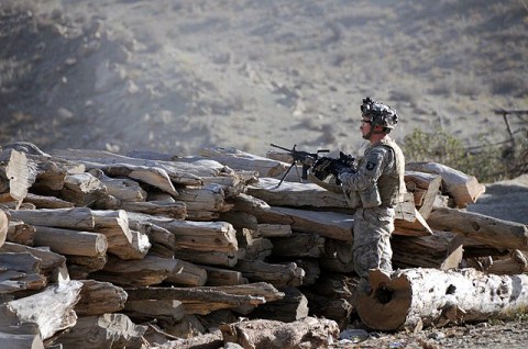 U.S. Army Pfc. Randall Kinnaman from Norman, OK, with E Company, 2nd Battalion, 506th Infantry Regiment, 4th Brigade Combat Team, 101st Airborne Division, provides security behind a log pile in a village in the Charbaran District here Oct. 28th during Task Force White Currahee Toccoa Tikurah. (Photo by U.S. Army Spc. Luther L. Boothe Jr., Task Force Currahee Public Affairs Office)