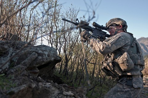 U.S. Army Spc. Brit B. Jacobs, a combat medic from Sarasota, fires his M4 rifle from a remote hilltop in the Shal Valley in eastern Afghanistan's Nuristan Province. (Photo by U.S. Army Staff Sgt. Mark Burrell, 210th Mobile Public Affairs Detachment)