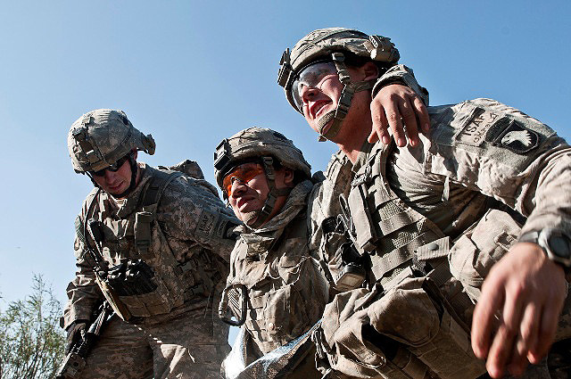 U.S. Army Spc. Brit B. Jacobs (right) and U.S. Army Sgt. Bryan Burgess (left), a squad leader from Cleburne, Texas, help out fellow Soldier U.S. Army Spc. Ronnie Vargas, a mortar man from Alice, Texas, make his way to the landing zone for medical evacuation during a firefight on a hilltop in the Shal Valley in eastern Afghanistan's Nuristan Province Nov. 7th. (Photo by U.S. Army Staff Sgt. Mark Burrell, 210th Mobile Public Affairs Detachment)