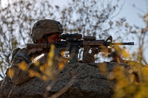 NURISTAN PROVINCE, Afghanistan – Using a boulder as cover on a mountaintop in the Shal Valley in eastern Afghanistan's Nuristan Province, U.S. Army Sgt. James T. Schmidt, Task Force No Slack, searches for insurgent activity, Nov. 8th. (Photo by U.S. Army Staff Sgt. Mark Burrell, 210th Mobile Public Affairs Detachment)