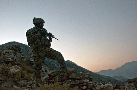 As the sun begins to rise, U.S. Army Staff Sgt. McCarthy Phillip, an infantry squad leader from Decatur, GA, assigned to Company C, 1st Battalion, 327th Infantry Regiment, Task Force Bulldog, scans the Pech River Valley for insurgent movement in eastern Afghanistan's Kunar Province Nov. 20th. “We’re up here doing an over watch and trying to stop any type of movement in the trails,” said Phillip. (Photo by U.S. Army Staff Sgt. Mark Burrell, Task Force Bastogne Public Affairs Office)