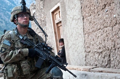 A teenage boy looks outside his door as U.S. Army Marcos E. Figueroa, a radio operator from Corozal, Puerto Rico, assigned to Company C, 1st Battalion, 327th Infantry Regiment (Task Force Bulldog), 101st Airborne Division, provides security during a patrol.  (Photo by U.S. Army Staff Sgt. Mark Burrell, Task Force Bastogne Public Affairs)