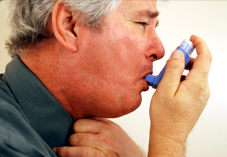 A man with COPD takes a shot from his inhaler A man with COPD takes a shot from his inhaler