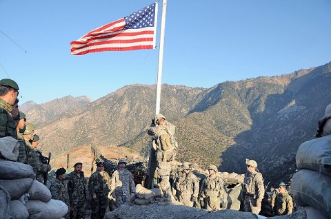 A noncommissioned officer with Troop C, 1st Squadron, 32nd Cavalry Regiment, 1st Brigade Combat Team, 101st Airborne Division prepares to lower the American flag during a transfer-of-authority ceremony at Observation Post Mace, as U.S. and Afghan National Army troops look on Dec. 21st. (Photo by U.S. Air Force Capt. Peter Shinn, Task Force Bastogne)