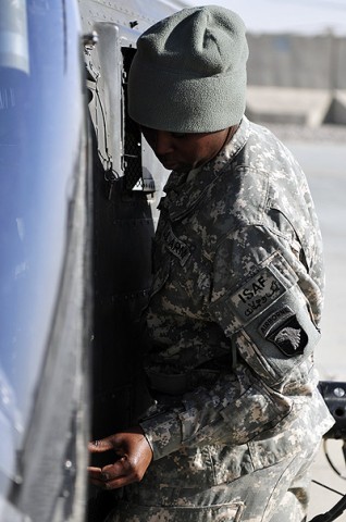 Pfc. May Riley, D Troop, Task Force Saber OH-58D Kiowa Warrior helicopter repairer removes the side doors from an aircraft during sling load training Dec. 2nd, 2010 at Kandahar Airfield, Afghanistan. (Photo by Spc. Tracy Weeden)