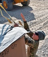 U.S. Army Sgt. Shannon Osterholm, a truck driver from Des Moines, Iowa with the 2168 Transportation Detachment, throws a ratchet strap over a box loaded with mail Dec. 18th at Forward Operating Base Fenty. In her civilian life, Osterholm is a zookeeper at the Blank Park Zoo in Des Moines, IA. (Photo by U.S. Army Staff Sgt. Ryan C. Matson, Task Force Red Bulls Public Affairs)