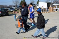 A woman and her two children walk back to their car after picking up a basket of food.