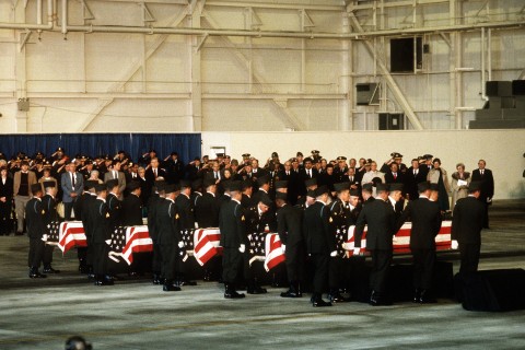 Mourners looks on as members of the 101st Airborne Division carry a casket containing the remains of members of the 3rd Bn., 502nd Inf., 101st Airborne Div., into a hangar for a memorial service. On December 12, 1985, 248 soldiers of the 3rd Battalion were killed in a plane crash at the Gander Airport, Newfoundland, Canada. They were returning to the United States after participating in peacekeeping duty with the Multi-national Force and Observers in the Sinai Desert.