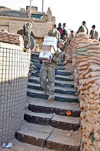 U.S. Army Pfc. Zach Hanood, a mortarman with Company A, 1st Battalion, 133rd Infantry Regiment, from Reinbeck, Iowa, carries a stack of holiday mail packages down the stairs at Combat Outpost Najil Dec. 24th. (Photo by U.S. Army Staff Sgt. Ryan C. Matson, Task Force Red Bulls Public Affairs)