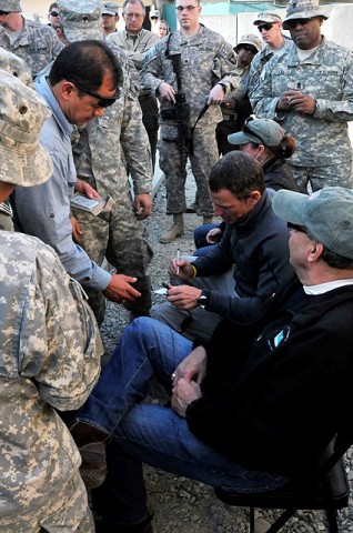 Comedians Lewis Black and Kathleen Madigan, along with athlete Lance Armstrong, sign autographs for an excited crowd at the USO building during their tour at Forward Operating Base Fenty near Jalalabad Dec. 15th. (Photo by U.S. Army Spc. Richard Daniels Jr., Task Force Bastogne Public Affairs)