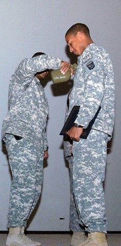 Water is poured on the rank of U.S. Army Sgt. Michael McReynolds during a noncommissioned officer induction ceremony at Bagram Airfield Jan. 21st. The rank is wetted to give his rank a worn appearance. (Photo by U.S. Army Spc. Adam L. Mathis, 17th Public Affairs Detachment)