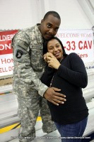 A newly returned soldier gently places his hand on his pregnant wifes bulging belly