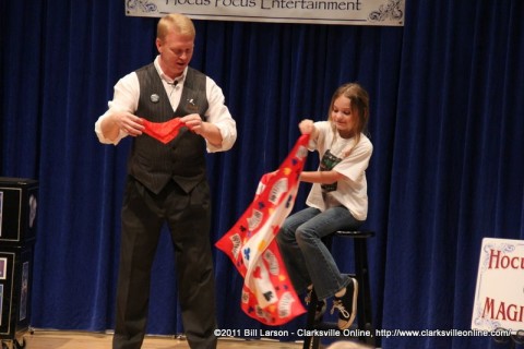 Magician Russ performs a trick with the assistance of an audience member