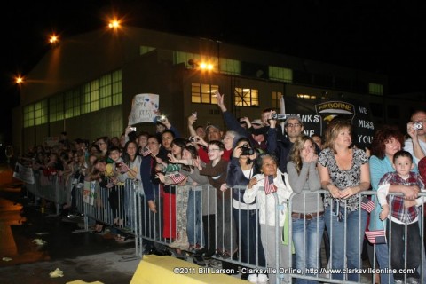 Family members call out to their loved ones as they pass by heading towards the hanger